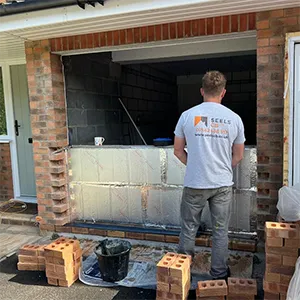 a man standing outside of a brick house